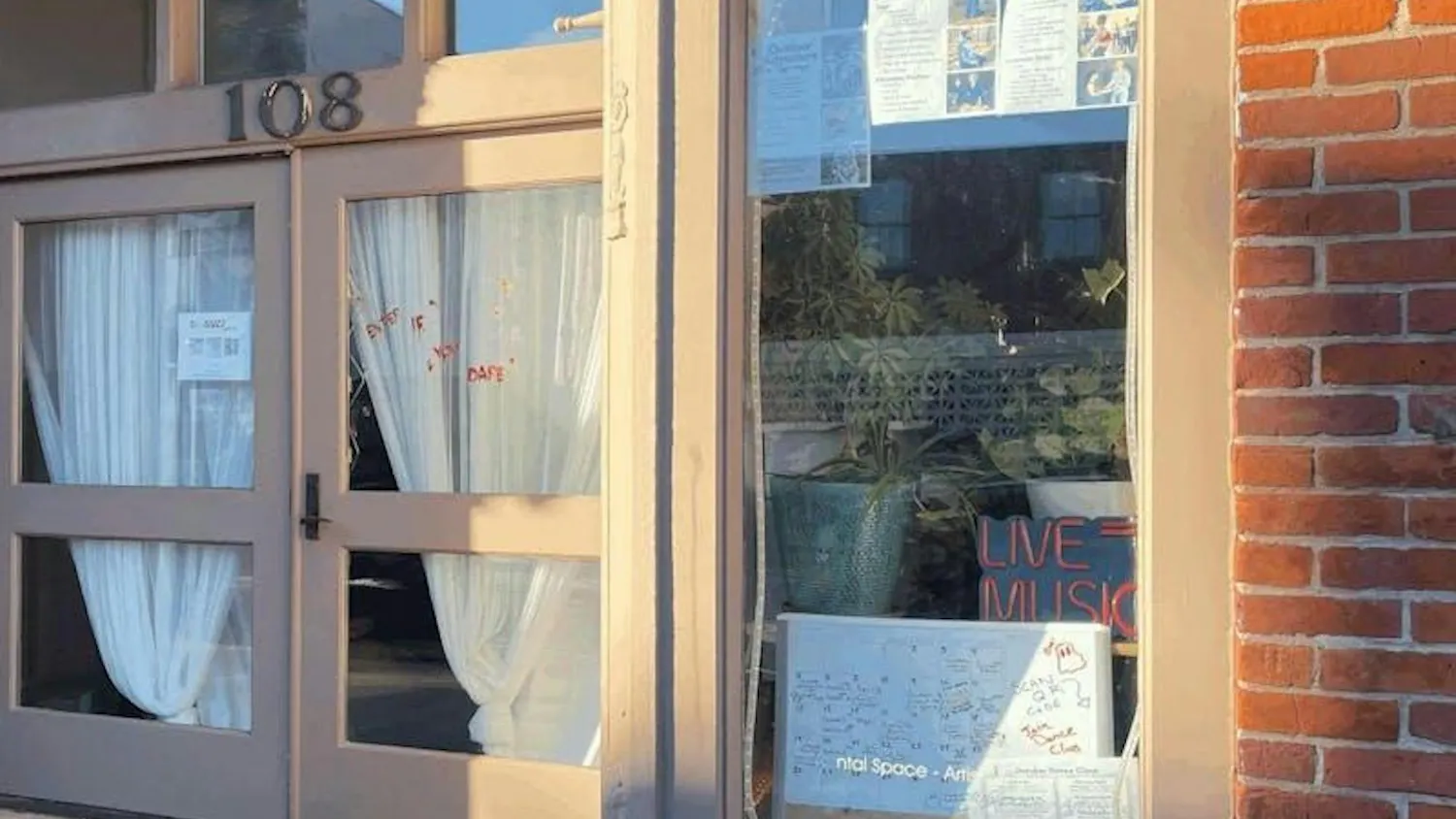 Front facade of Rhizome Roots with plants and posters in the window.