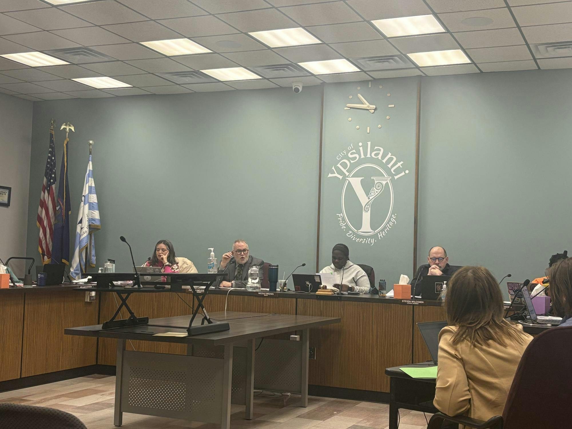 Seven Ypsilanti City Council members sit behind a large, shared, U-shaped desk and discuss topics during the meeting.