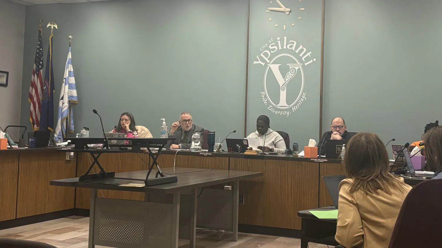 Seven Ypsilanti City Council members sit behind a large, shared, U-shaped desk and discuss topics during the meeting.