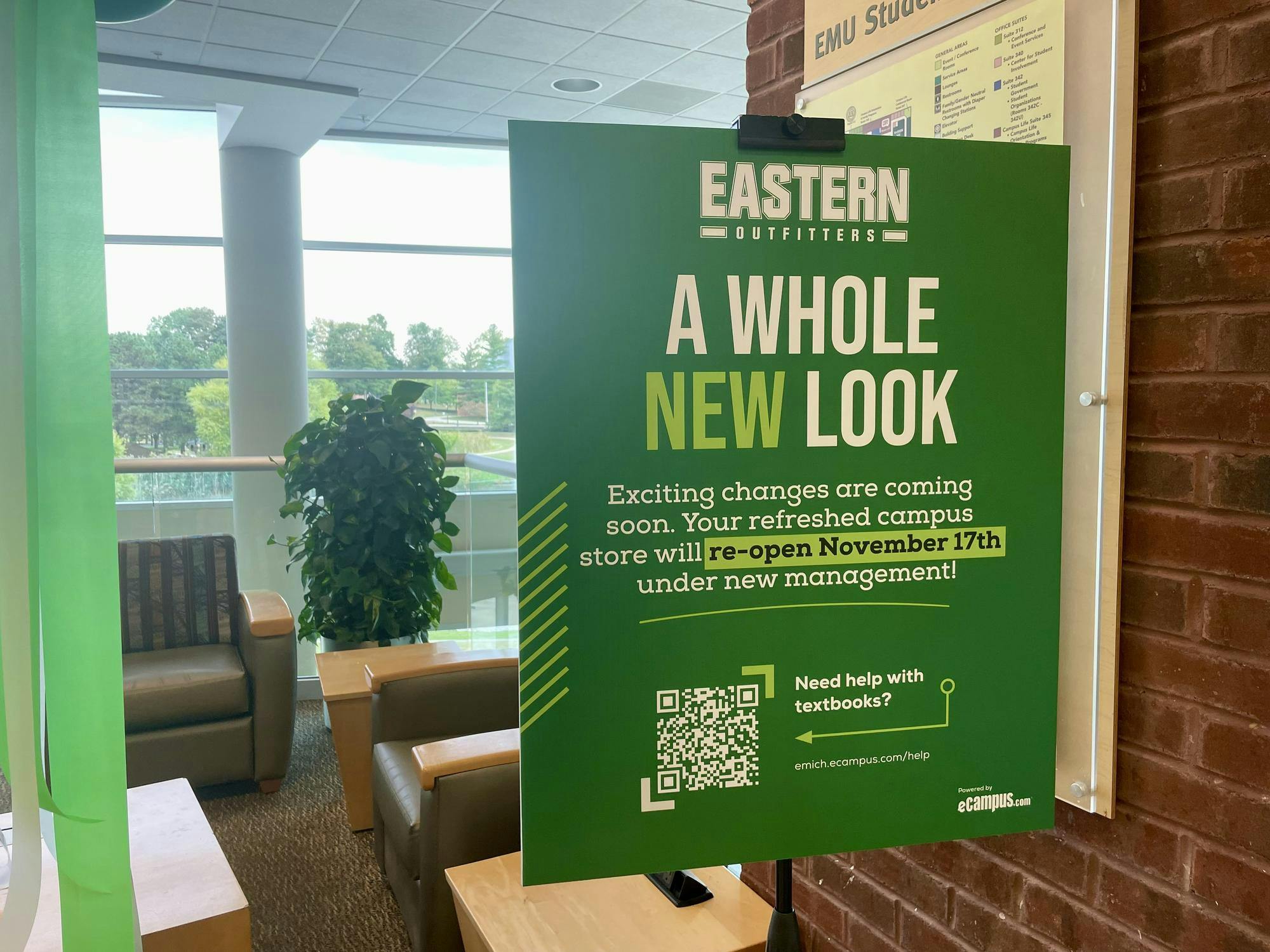 Green poster pasted to a window reading, "Eastern Outfitters, a whole new look. Exciting changes are coming soon."