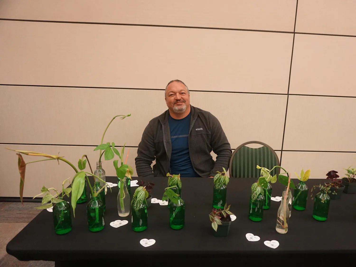 A view of Bradley Cross posing for a picture behind a table of plants grown on campus.