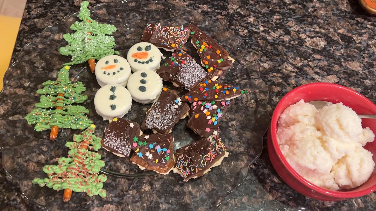 A photo of snow cream, snowmen made with two Oreos coated in white chocolate, chocolate covered toffee crackers, and Christmas trees made from pretzel sticks and green-dyed white chocolate.