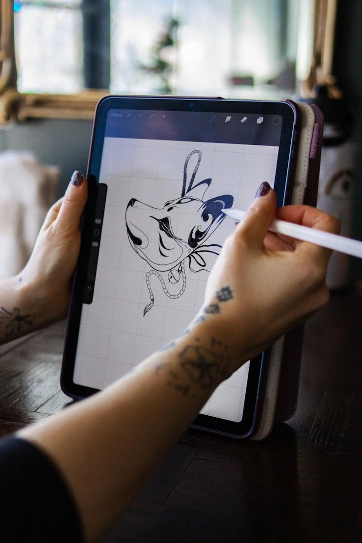 Close-up drawing of the head of a wolf on a drawing tablet, showing only the tablet and the artist's hands.