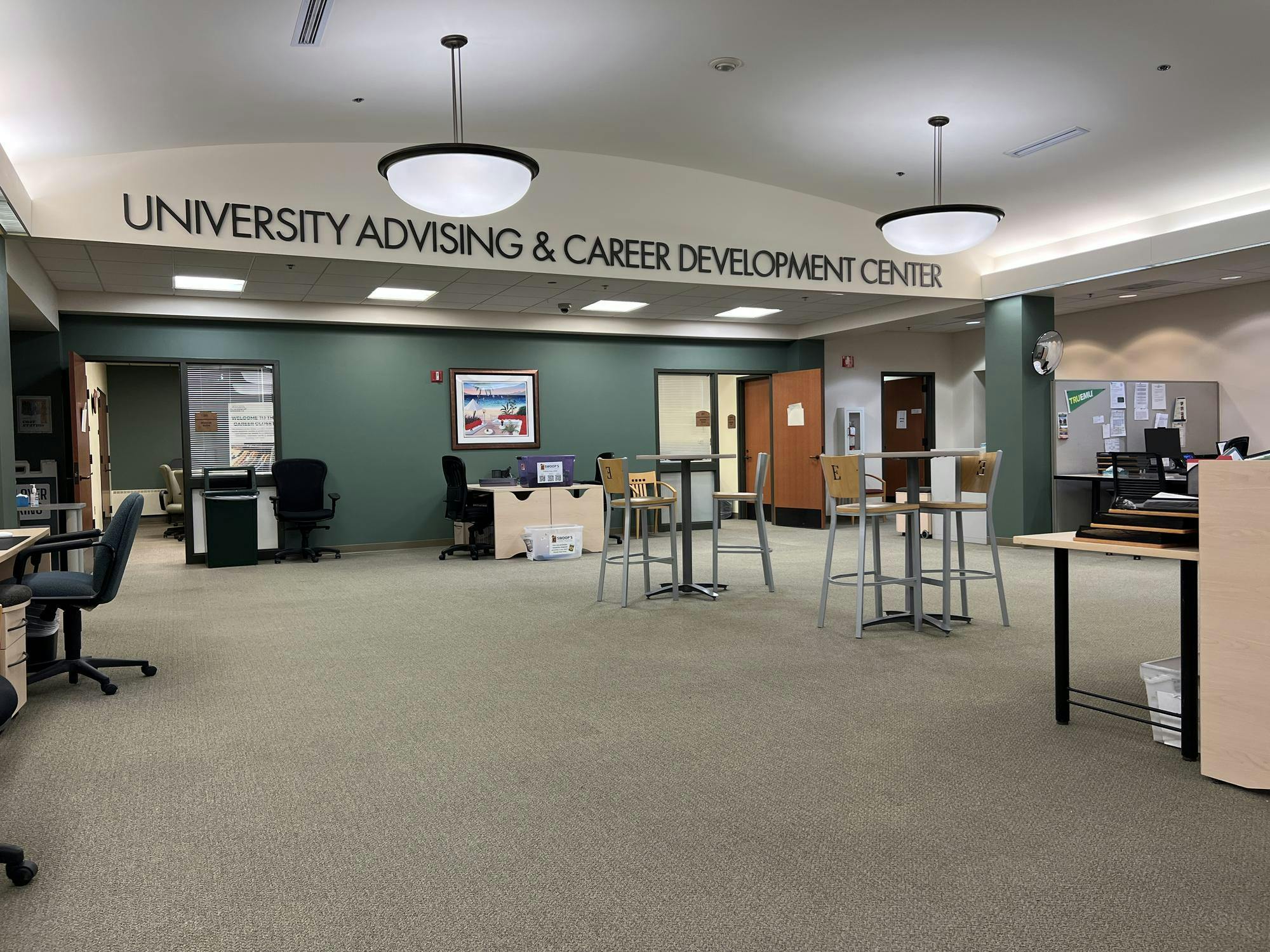 A wide room with an open layout has letters spelling out "University Advising & Career Development Center" near an arching ceiling.