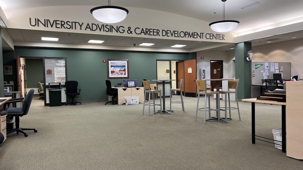 A wide room with an open layout has letters spelling out "University Advising & Career Development Center" near an arching ceiling.