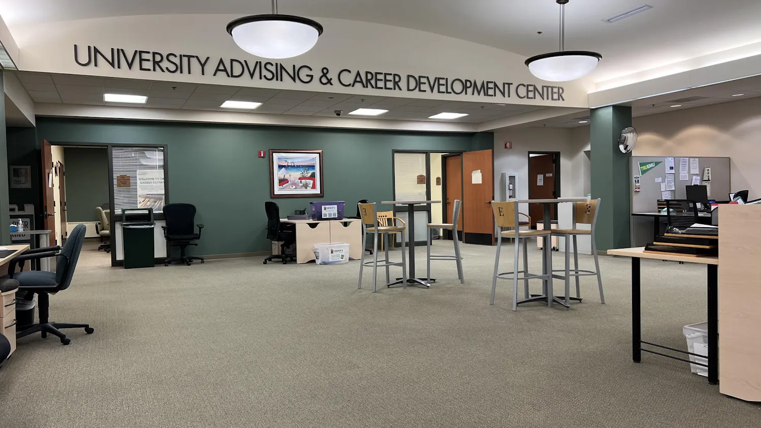 A wide room with an open layout has letters spelling out "University Advising & Career Development Center" near an arching ceiling.