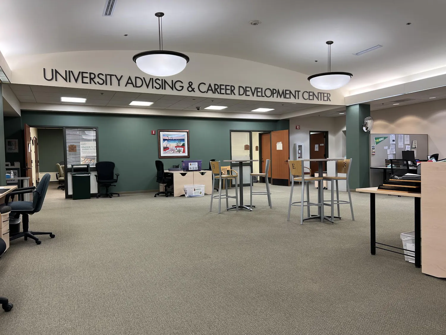 A wide room with an open layout has letters spelling out "University Advising & Career Development Center" near an arching ceiling.