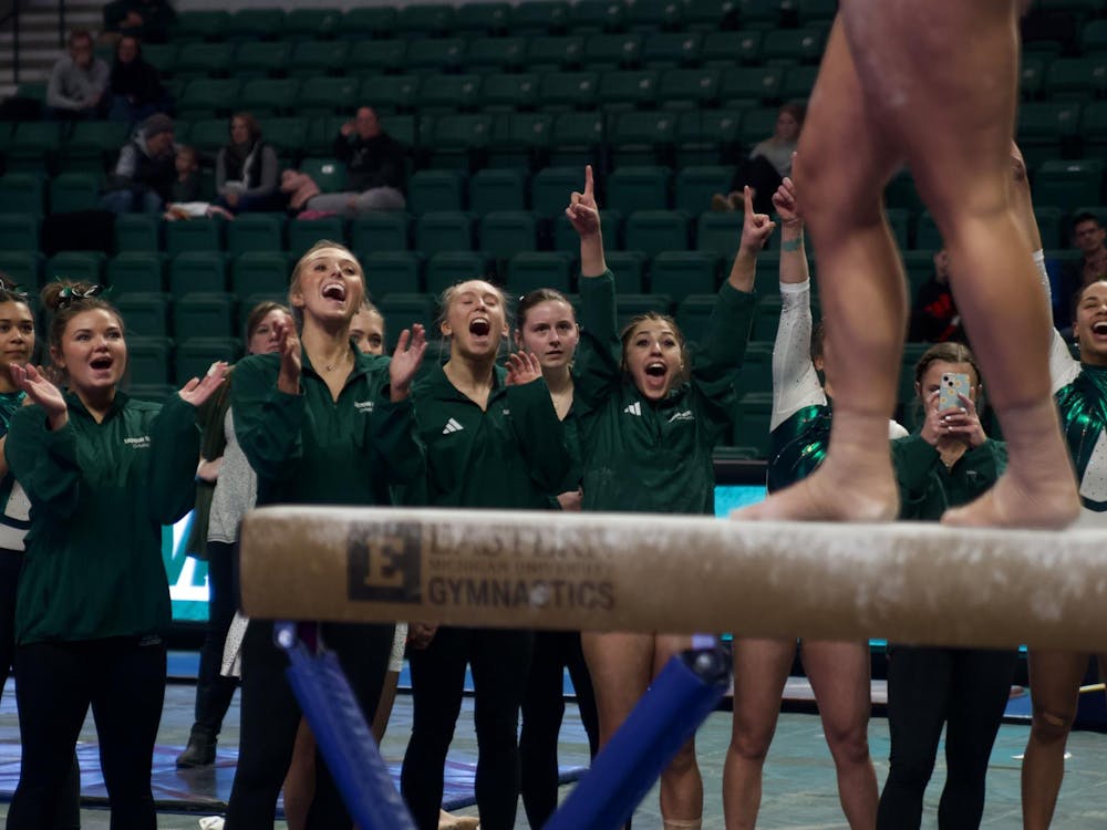 EMU's gymnasts cheer for their teammates on the balance beam. Photo taken February 17, 2024, at the George Gervin GameAbove Center.