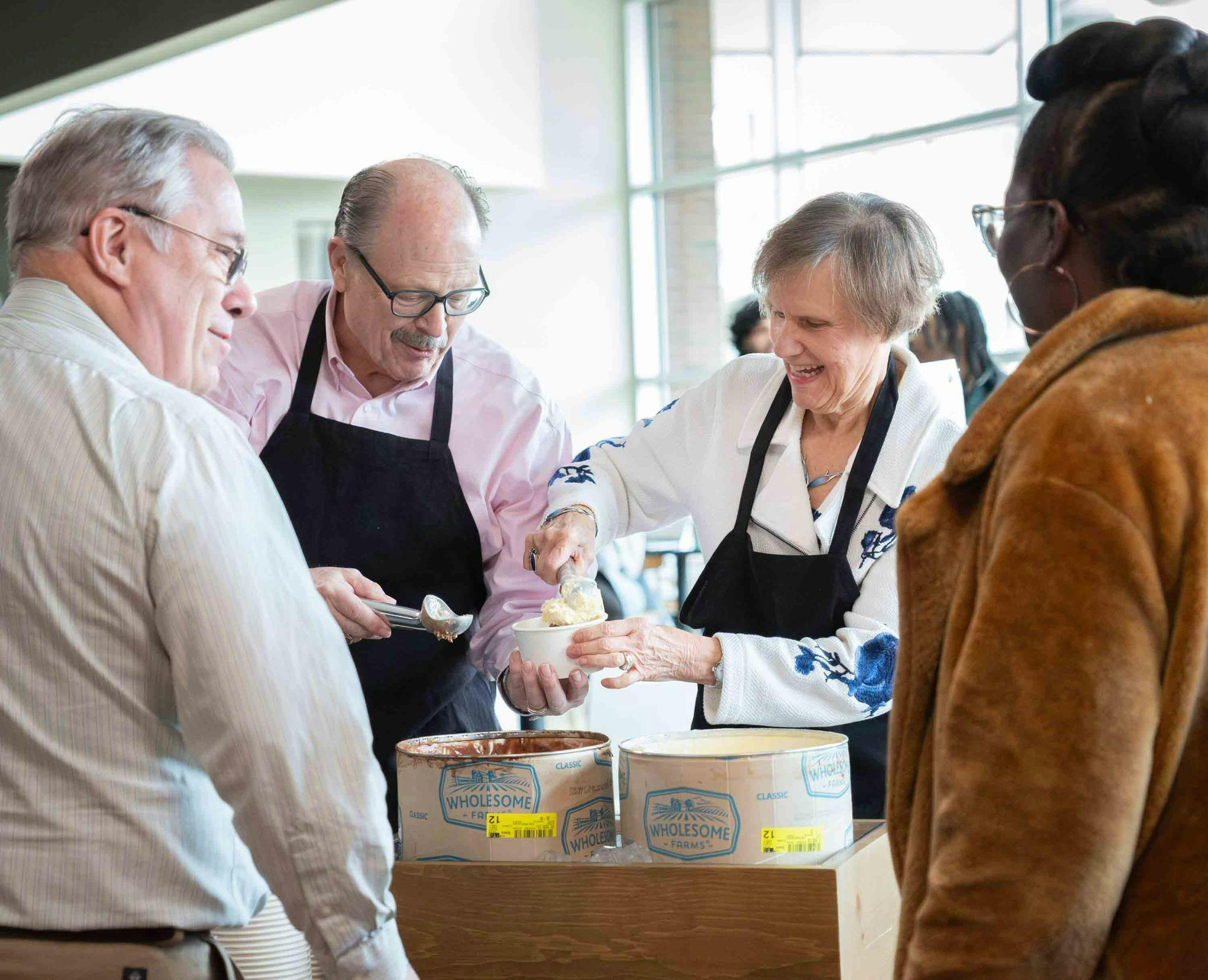 4 people pictured smiling and serving ice cream.