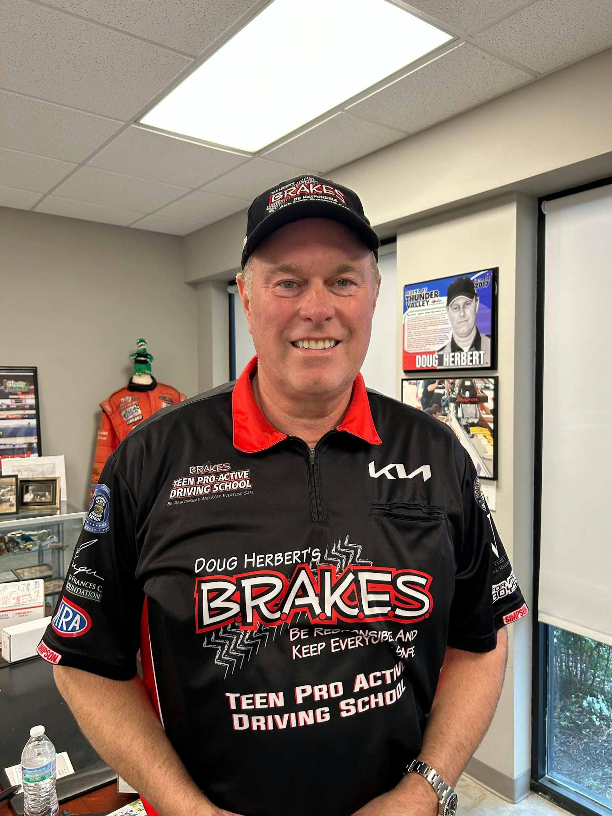 A man in a BRAKES branded hat and shirt smiles.