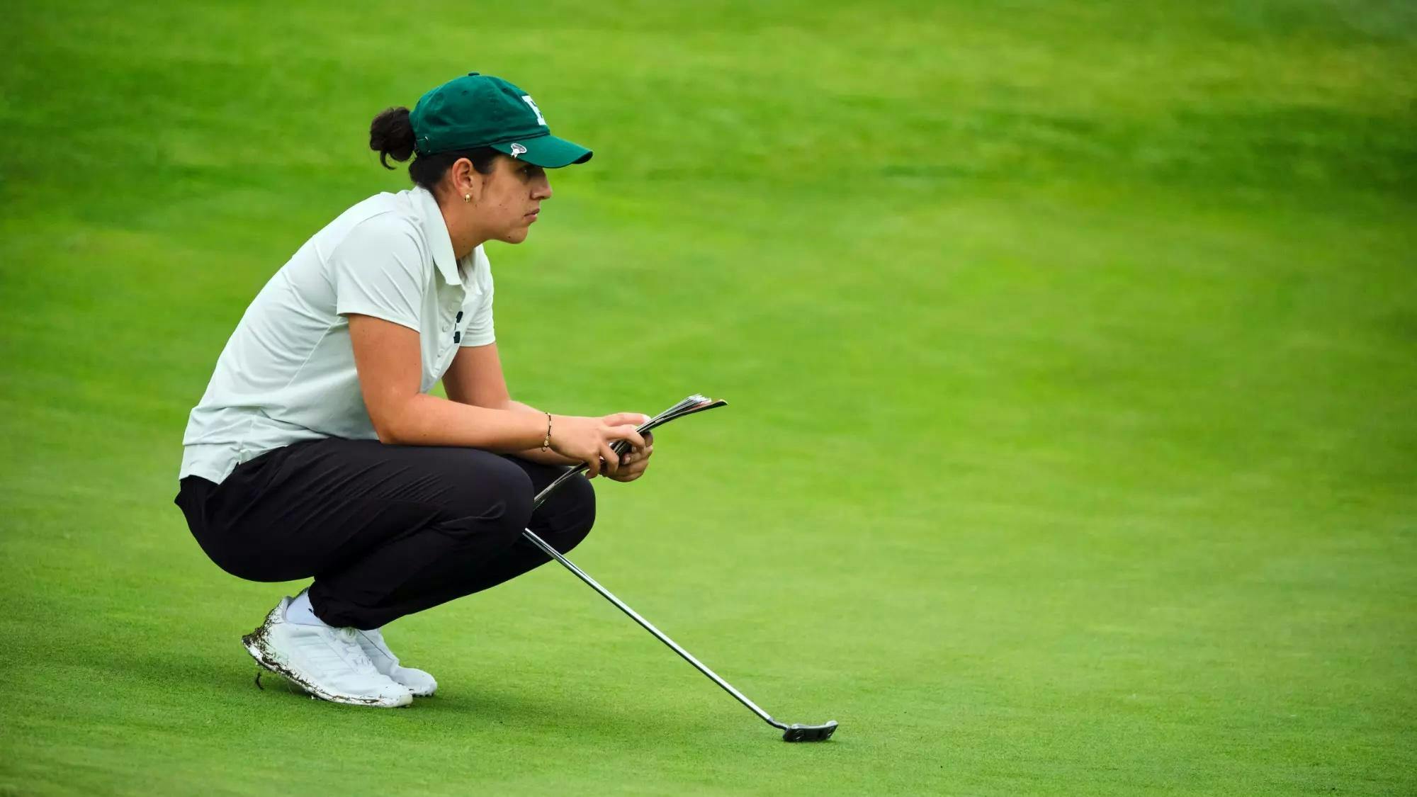 Mariana Vega crouches on golf course to think while gazing off into the distance.