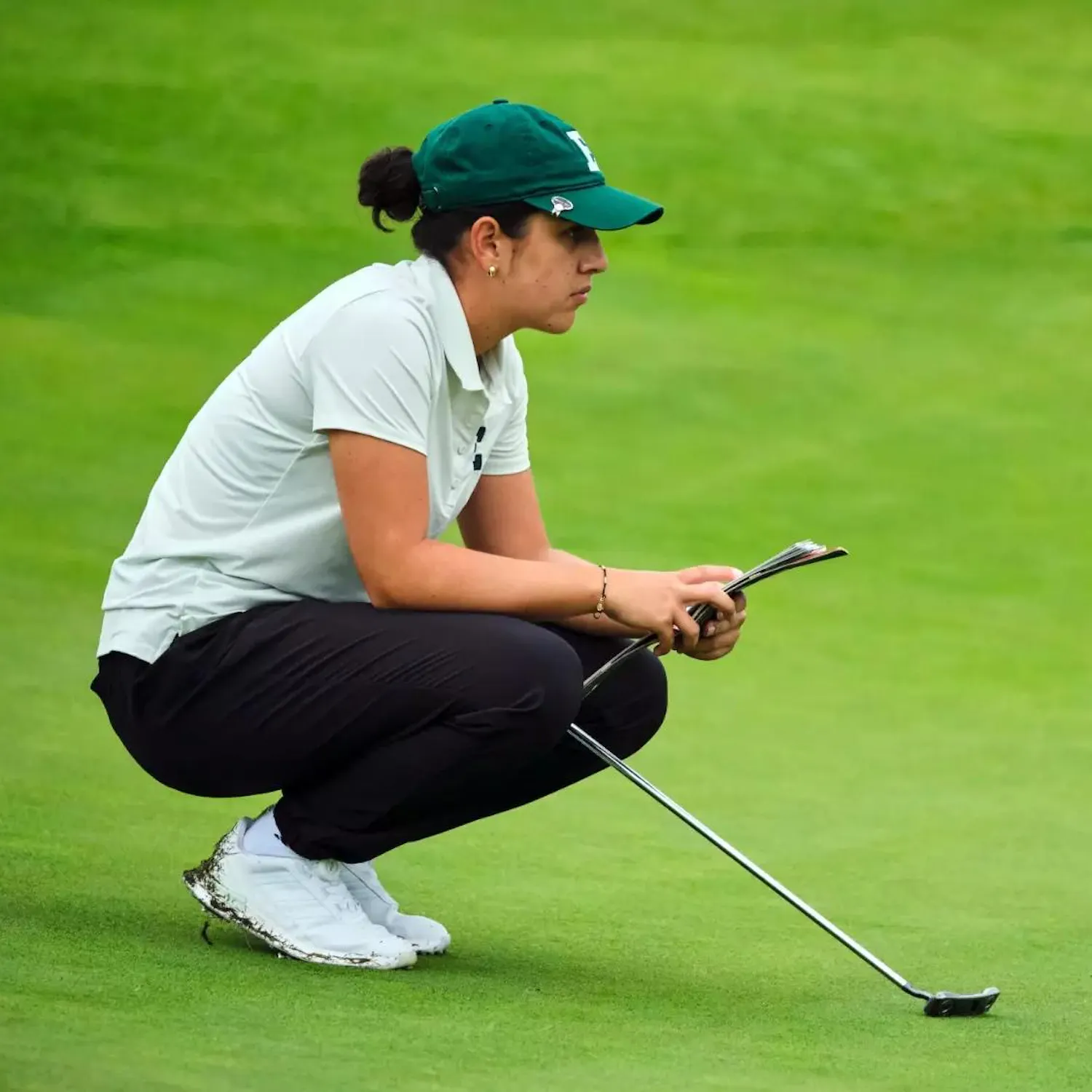 Mariana Vega crouches on golf course to think while gazing off into the distance.