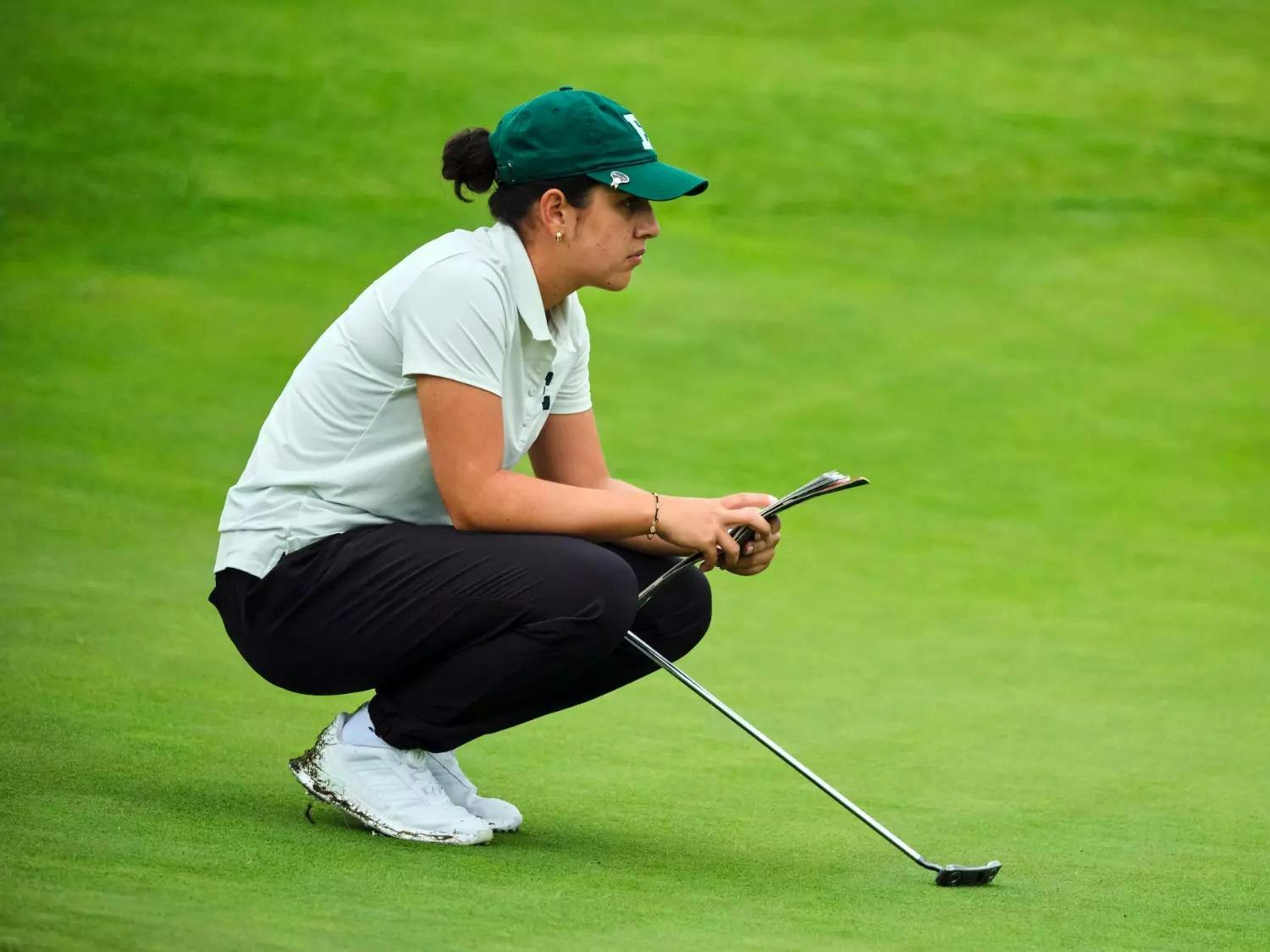 Mariana Vega crouches on golf course to think while gazing off into the distance.