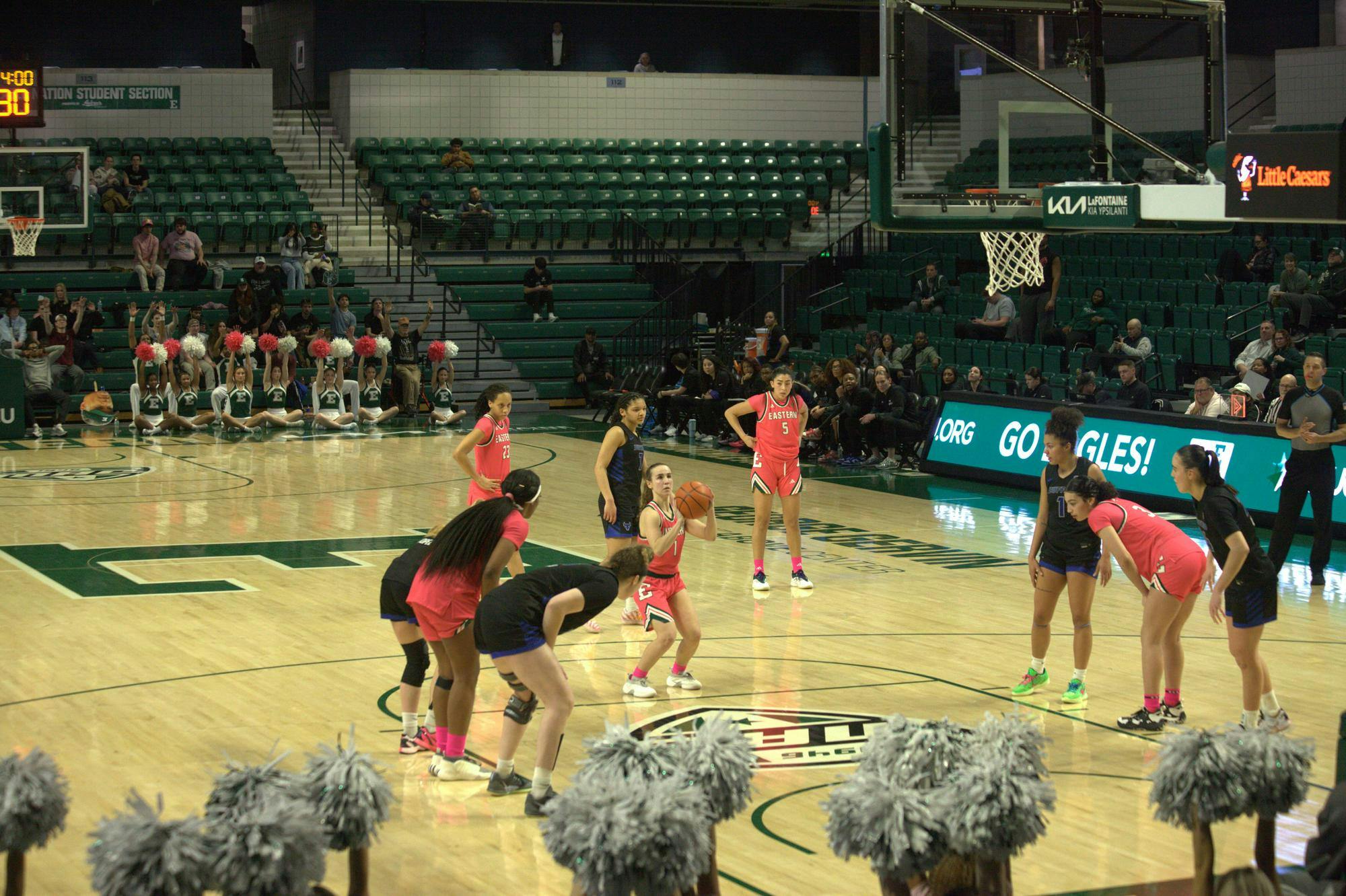 Women's basketball player aims a free throw while players of both teams are lined up on either side of the lane on an indoor court.