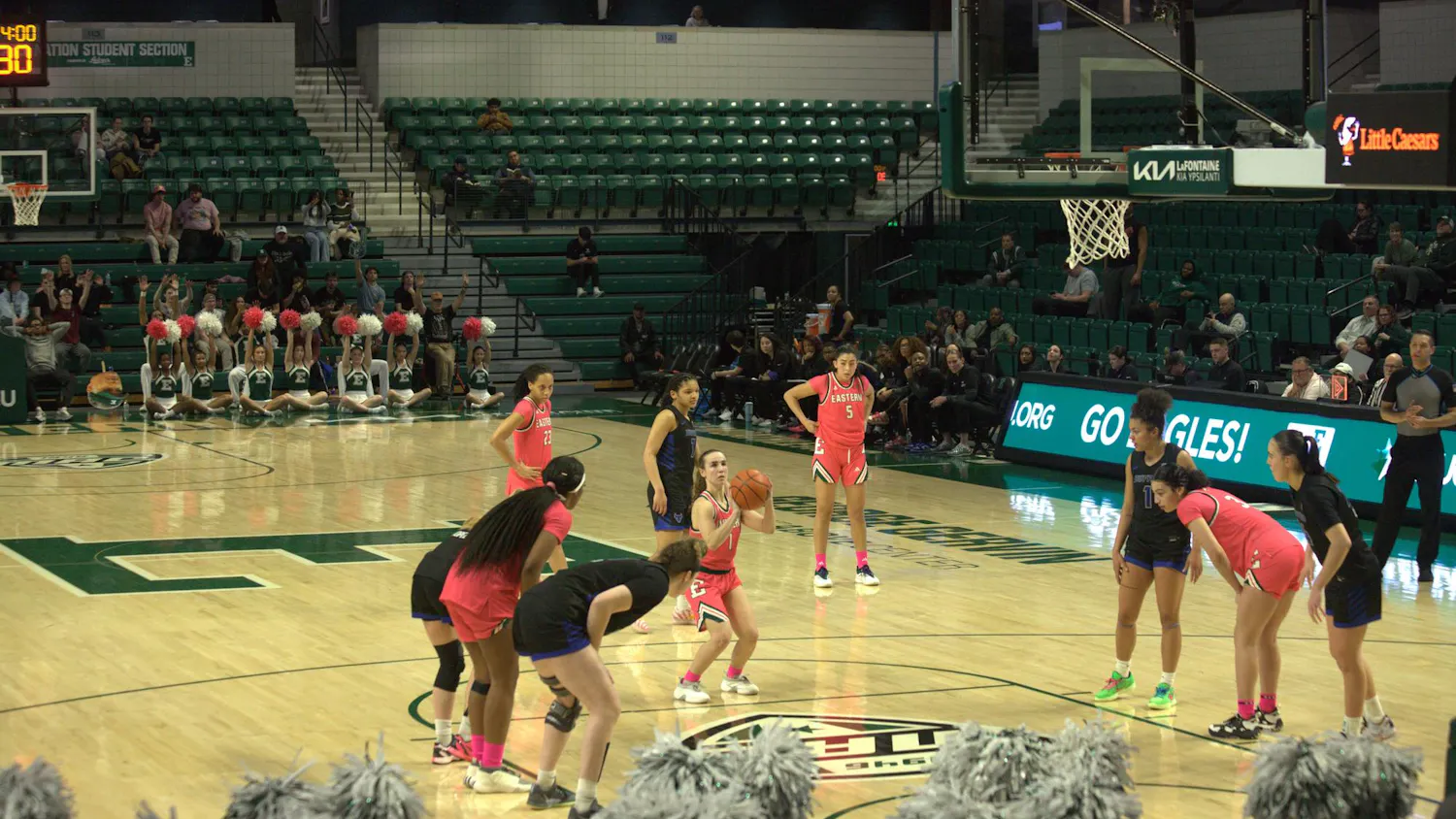 Women's basketball player aims a free throw while players of both teams are lined up on either side of the lane on an indoor court.