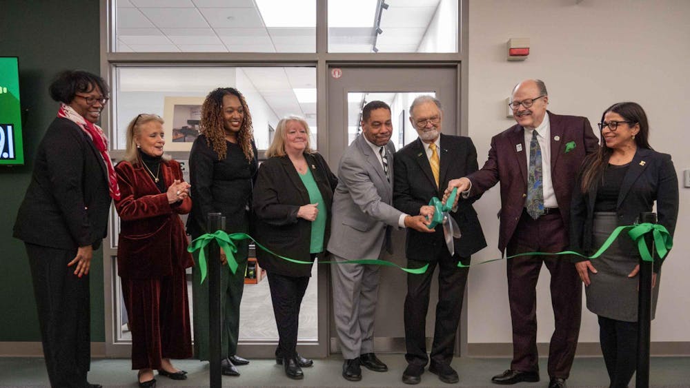 People clap and smile as Nate Ford, Art Timko, and James Smith hold oversized scissors and cut the green ribbon.