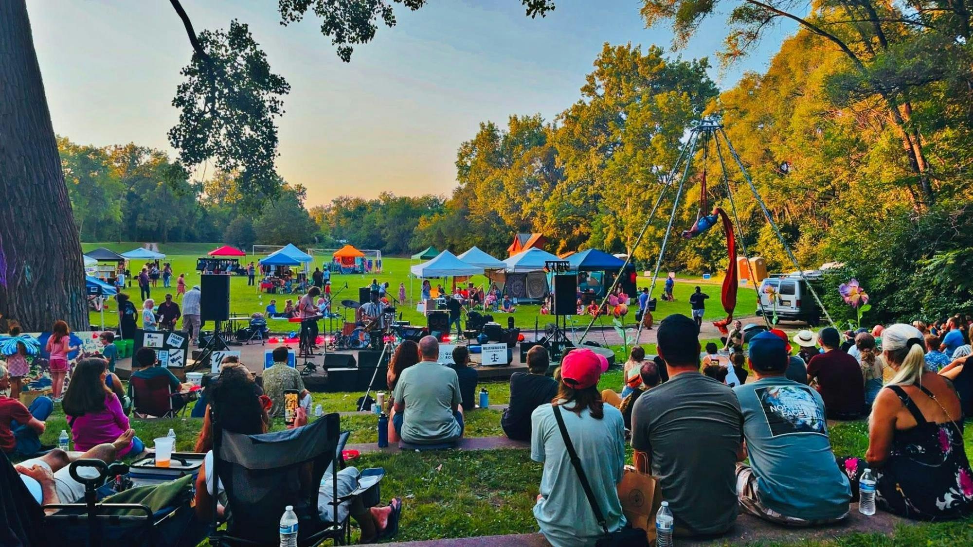 Groups of people sitting at a park for a concert.