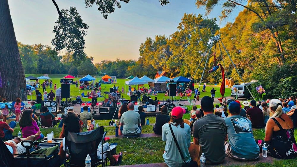 Groups of people sitting at a park for a concert.