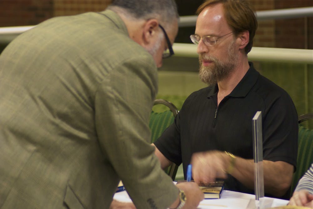 Author Lev Raphael autographs copies of his book, “My Germany,” which follows his return to his parents’ homeland, which they fled after WWII.