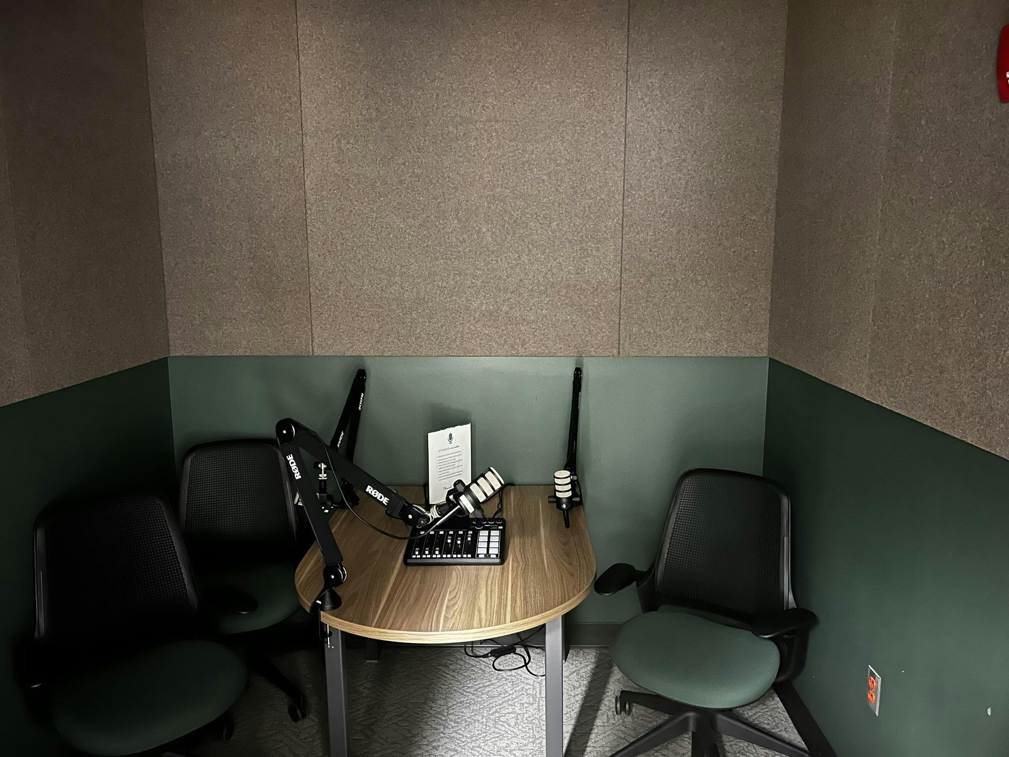 A small room with three chairs and microphones around a table with a small mixing board. 