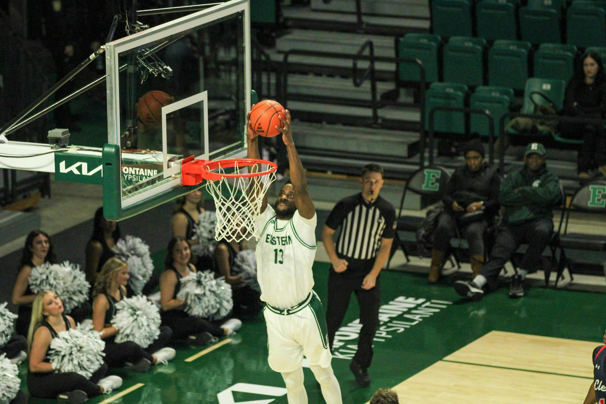 #13 Godslove Nwabude, in a white Eastern Michigan University jersey, dunking the ball. 