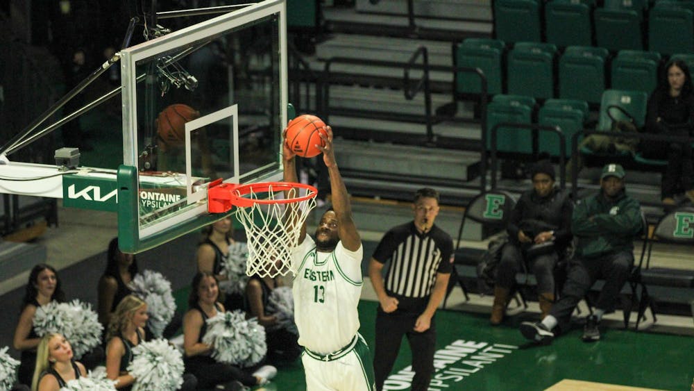 #13 Godslove Nwabude, in a white Eastern Michigan University jersey, dunking the ball.