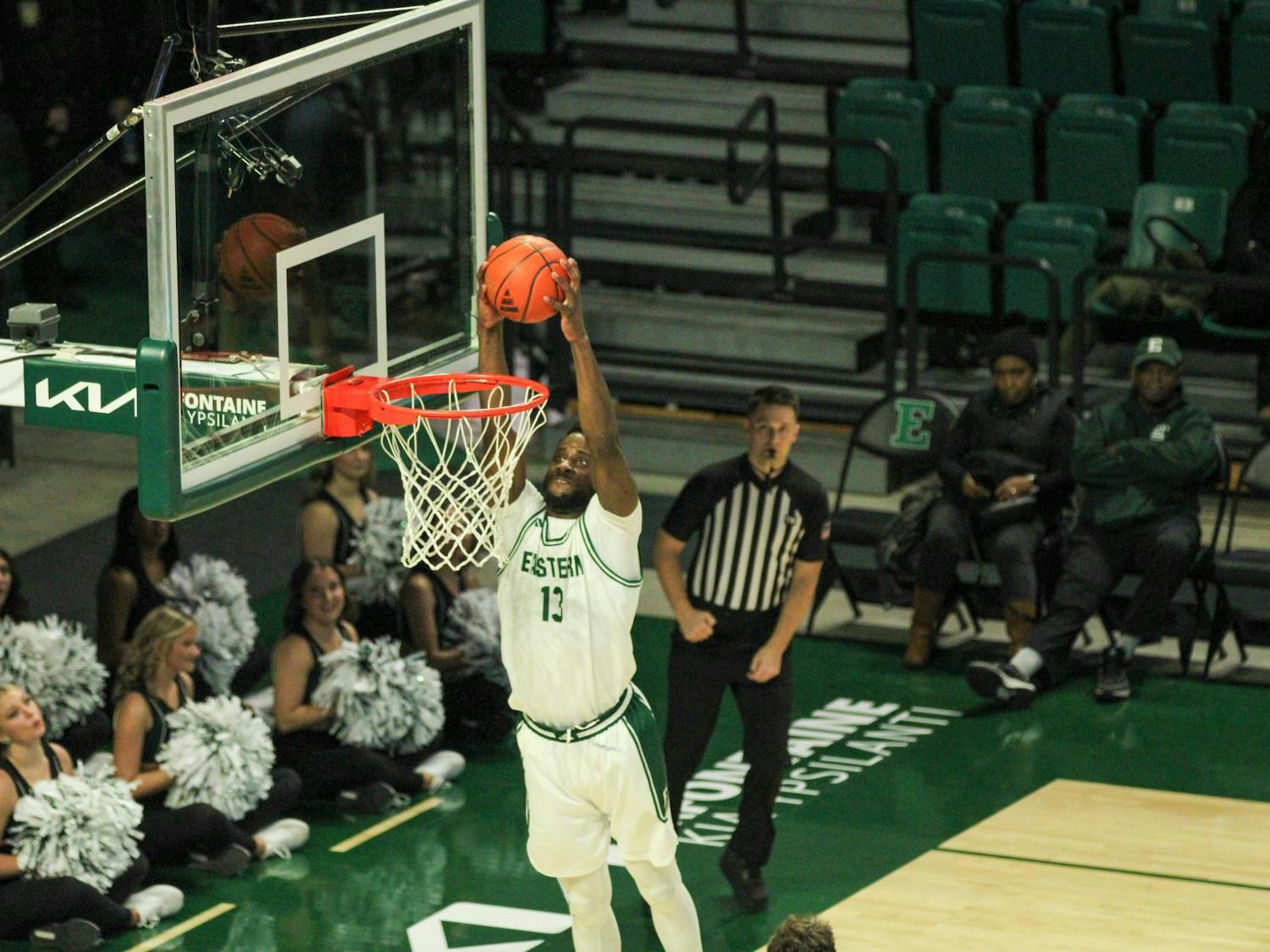 #13 Godslove Nwabude, in a white Eastern Michigan University jersey, dunking the ball.