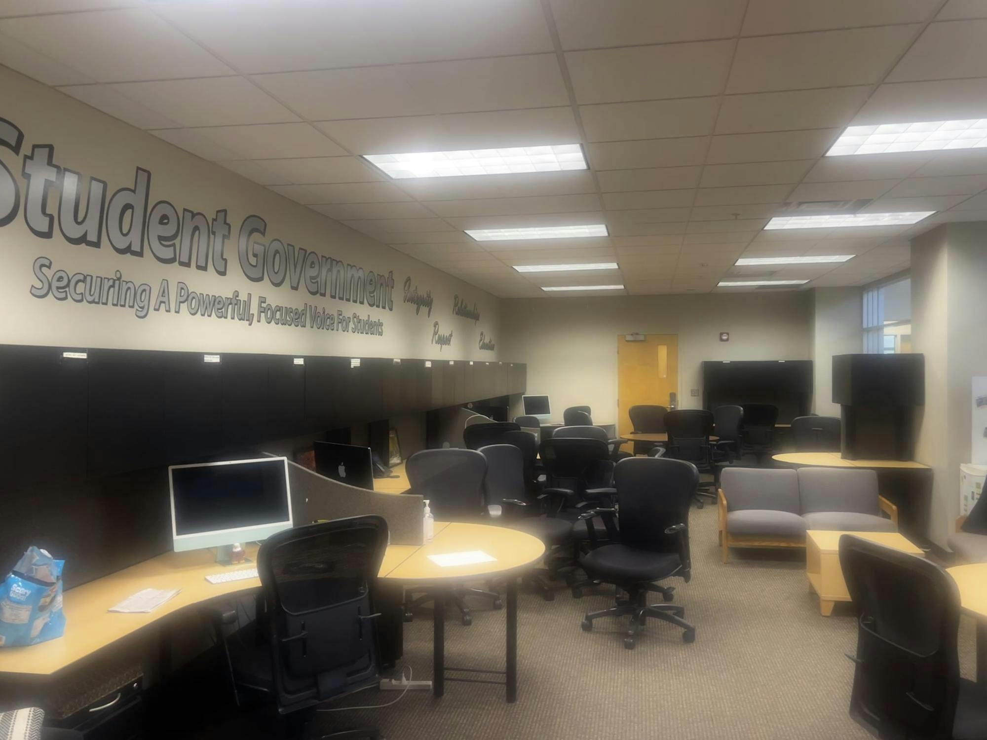An office space with several chairs, desks and computers. Lettering on the wall says "Student Government" and "Securing A Powerful, Focused Voice For Students."