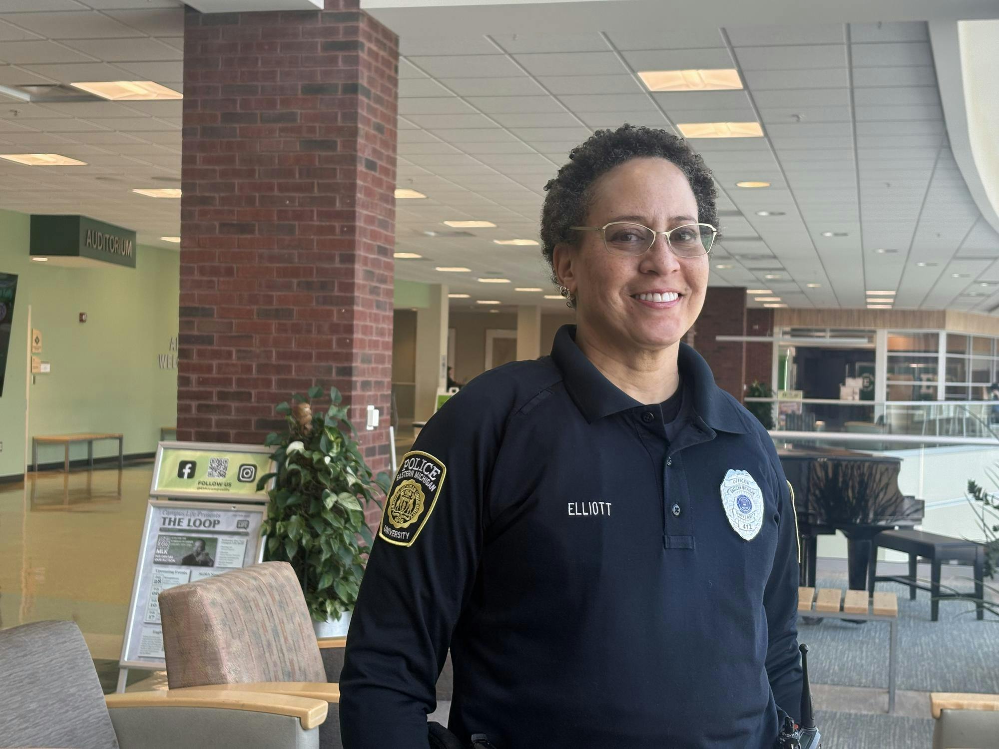 Officer Elliott smiles and stands in uniform in the Student Center.