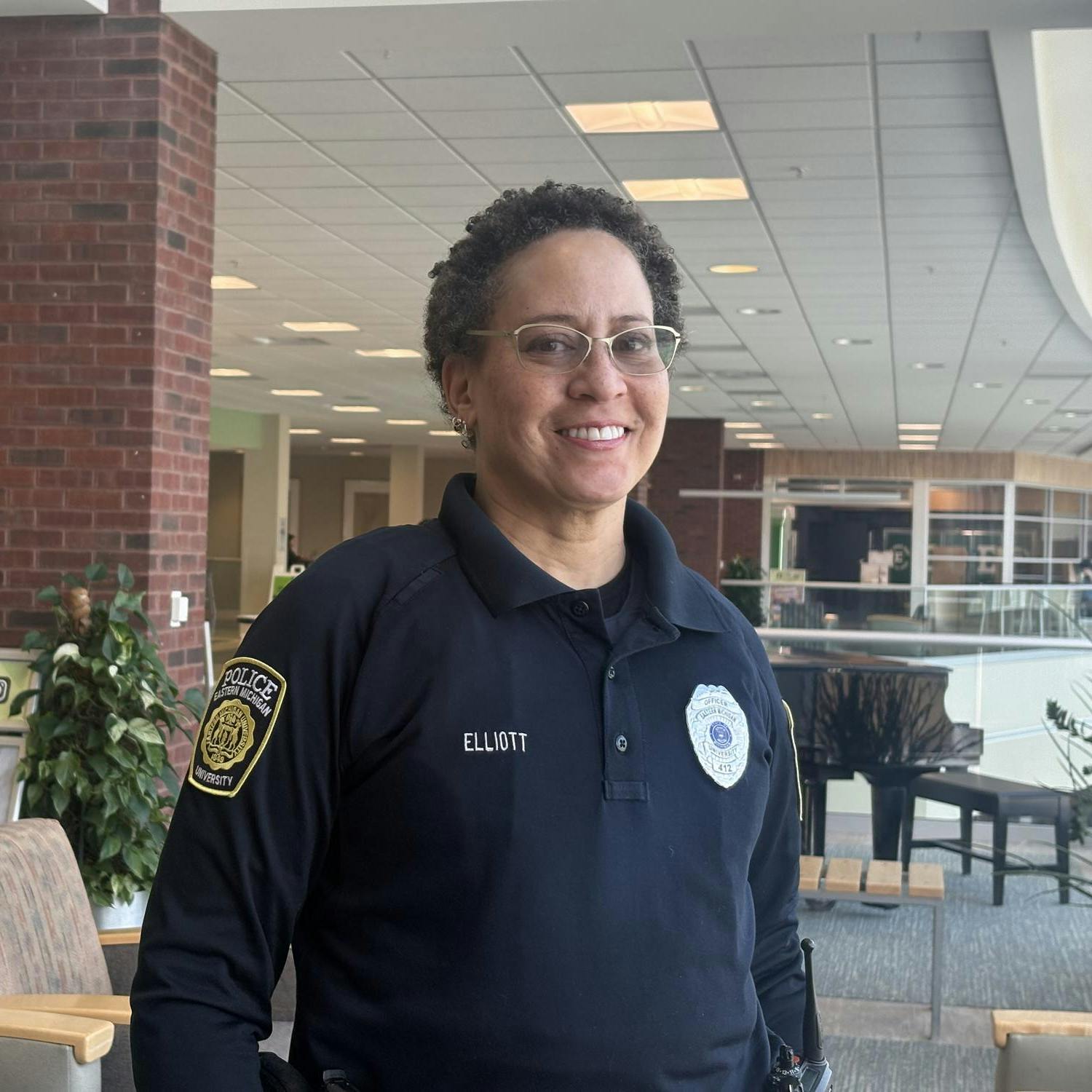 Officer Elliott smiles and stands in uniform in the Student Center.