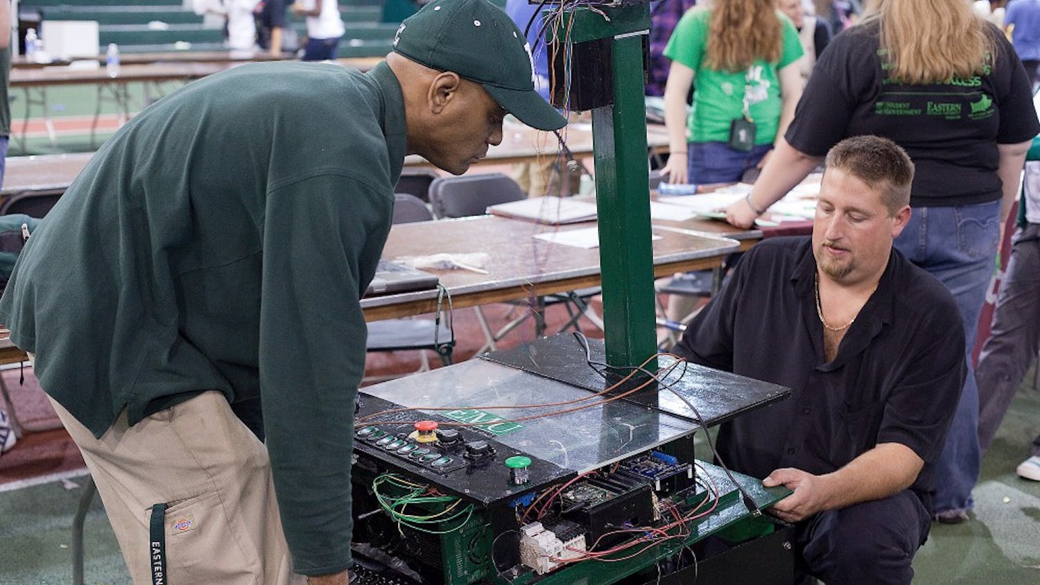 Nathan Jones (left), president of the Robotics Society at EMU, lifts the electronics and top of the new robot with some help from member Corey Horvath. The robot was present at this year's Fajita Fest in Bowen Field House.