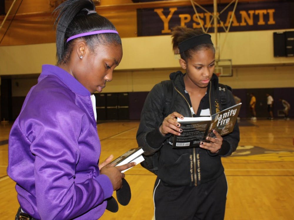 Carneysha McGee, left, and Cassandra Gibson select a few books during the Dec. 10 Book giveaway at Ypsilanti High School sponsored by the Michigan Education Association and the NFL.
