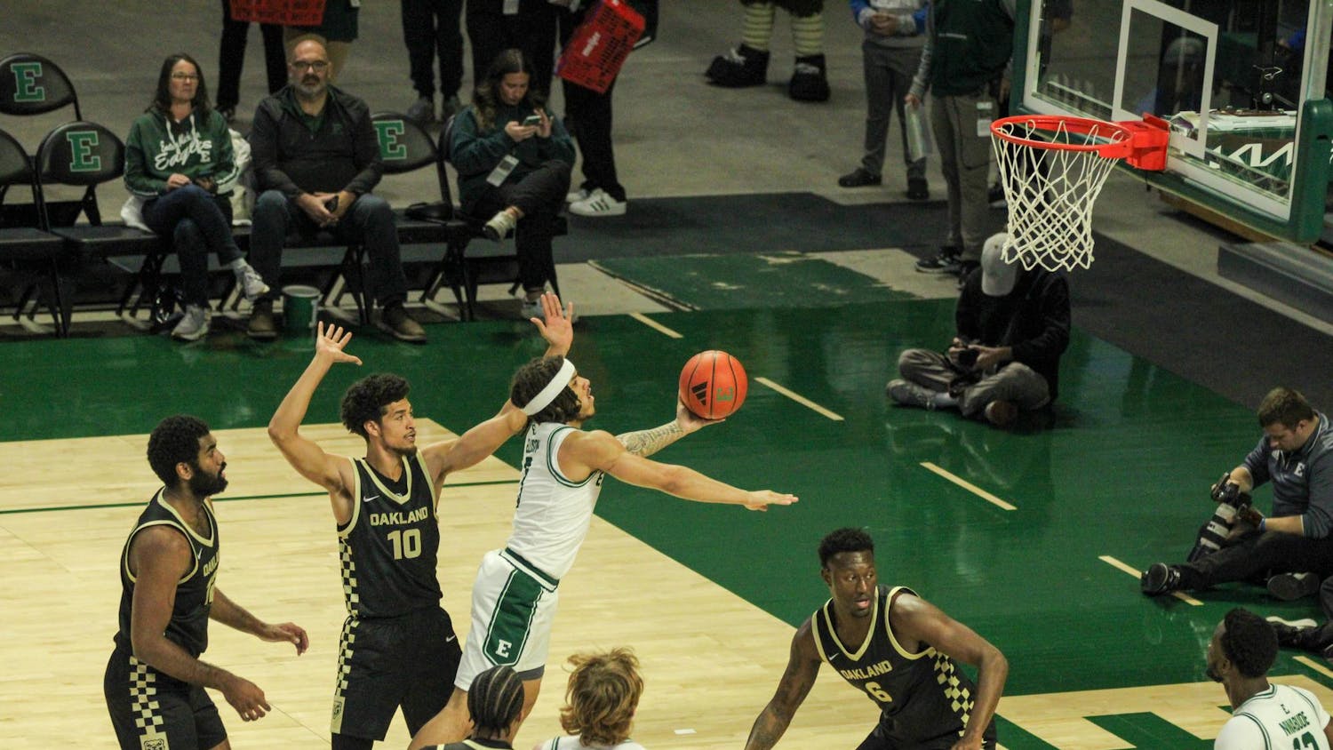 #3, in a white jersey, shooting with Oakland players around, in black jerseys.