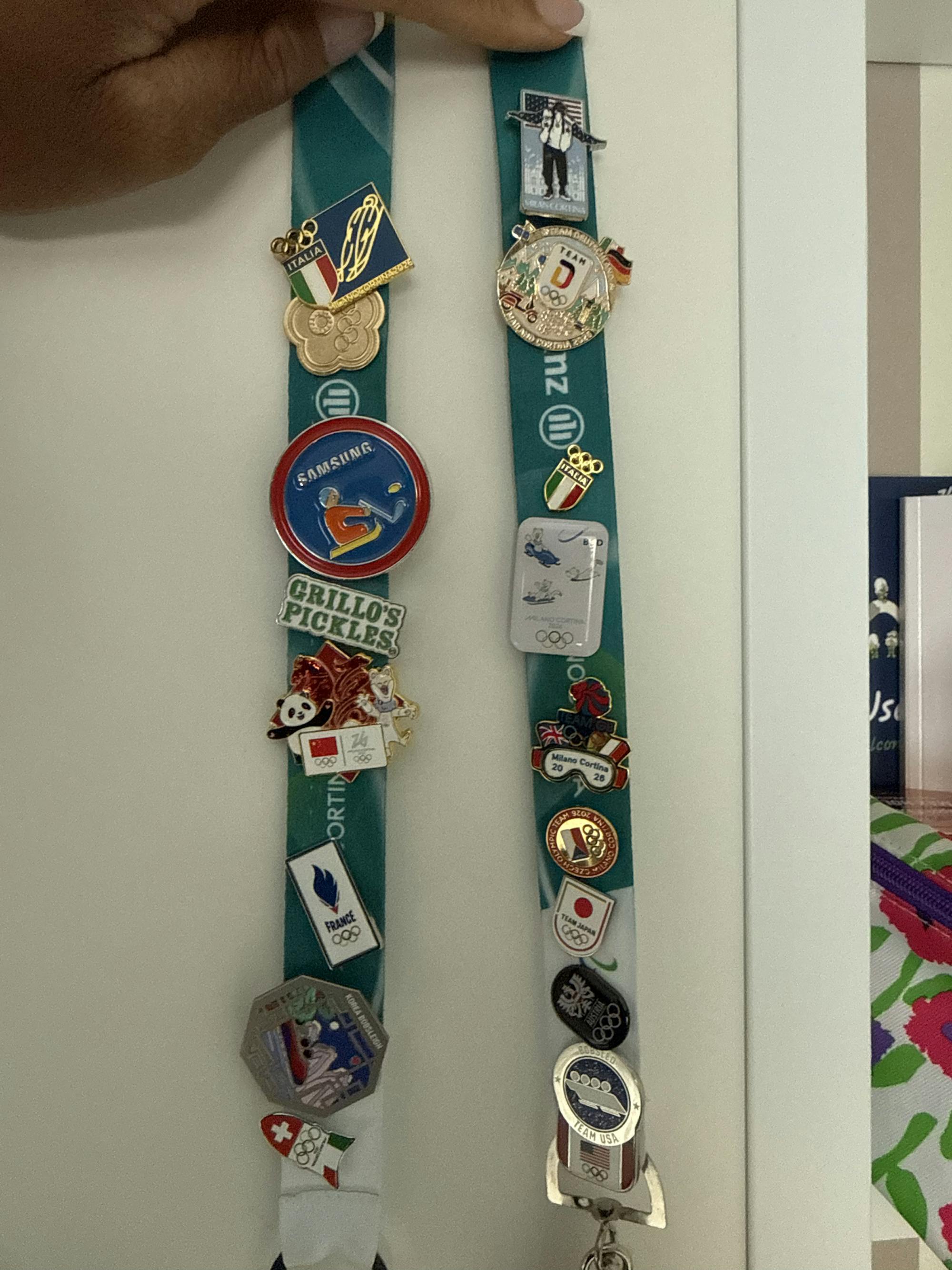 Many colorful Olympic pins are attached to a green lanyard, representing competitors from each country.