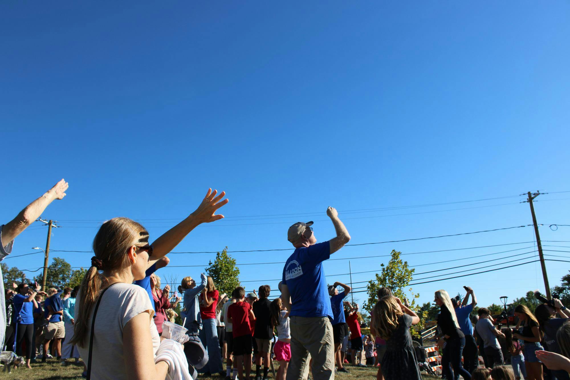 Hands are raised to block sun from eyes to see balloon launch....JPG