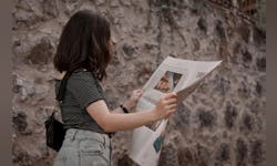A woman reads a newspaper. Photo credit by Unsplash.