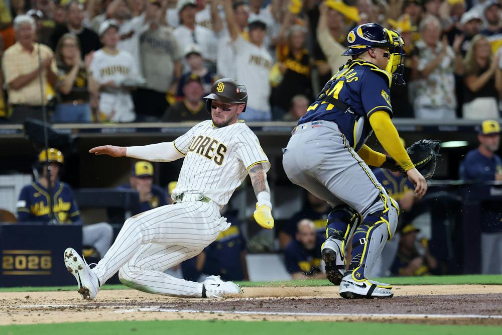 The San Diego Padres' Jackson Merrill, left, slides into home plate to score a run past Milwaukee Brewers catcher William Contreras (24) in the third inning in Game 3 of the National League Division Series at Petco Park on Tuesday, Oct. 6, 2026, in San Diego. (Sean M. Haffey/Getty Images/TNS)