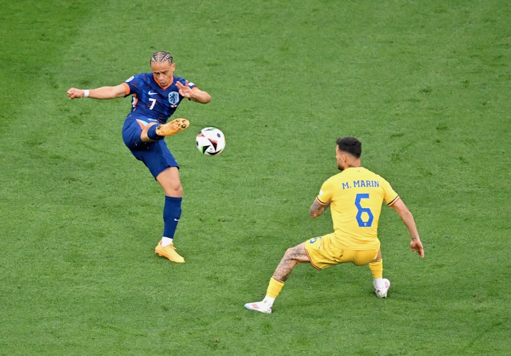 MUNICH, GERMANY – JULY 02: Xavi Simons of the Netherlands passes the ball whilst under pressure from Marius Marin of Romania during the UEFA EURO 2024 round of 16 match between Romania and Netherlands at Munich Football Arena on July 02, 2024 in Munich, Germany. (Photo by Chris Ricco – UEFA/UEFA via Getty Images)