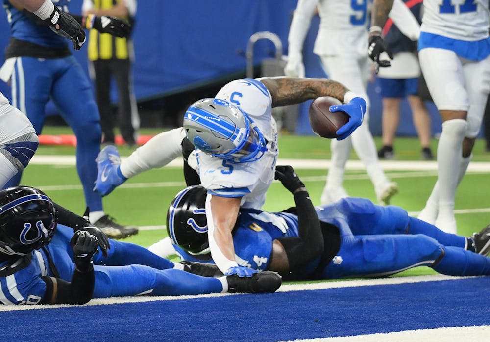 Detroit Lions running back David Montgomery stretches, spins and scores over Indianapolis Colts' Zaire Franklin and Jaylon Jones in the second quarter. (Daniel Mears, The Detroit News/Tribune Content Agency)