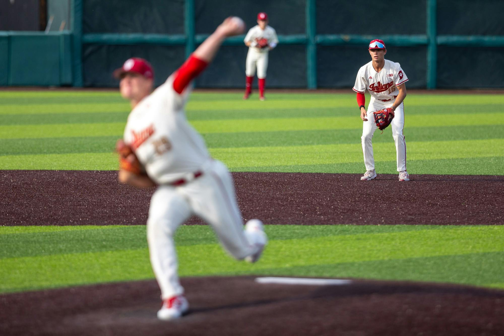 As Tony Neubeck delivers a pitch (foreground), Cooper Malamazian (15) gets into a defensive position during Indiana's win over Abilene Christian on April 17, 2026. (HN photo/Lauren McKinney)