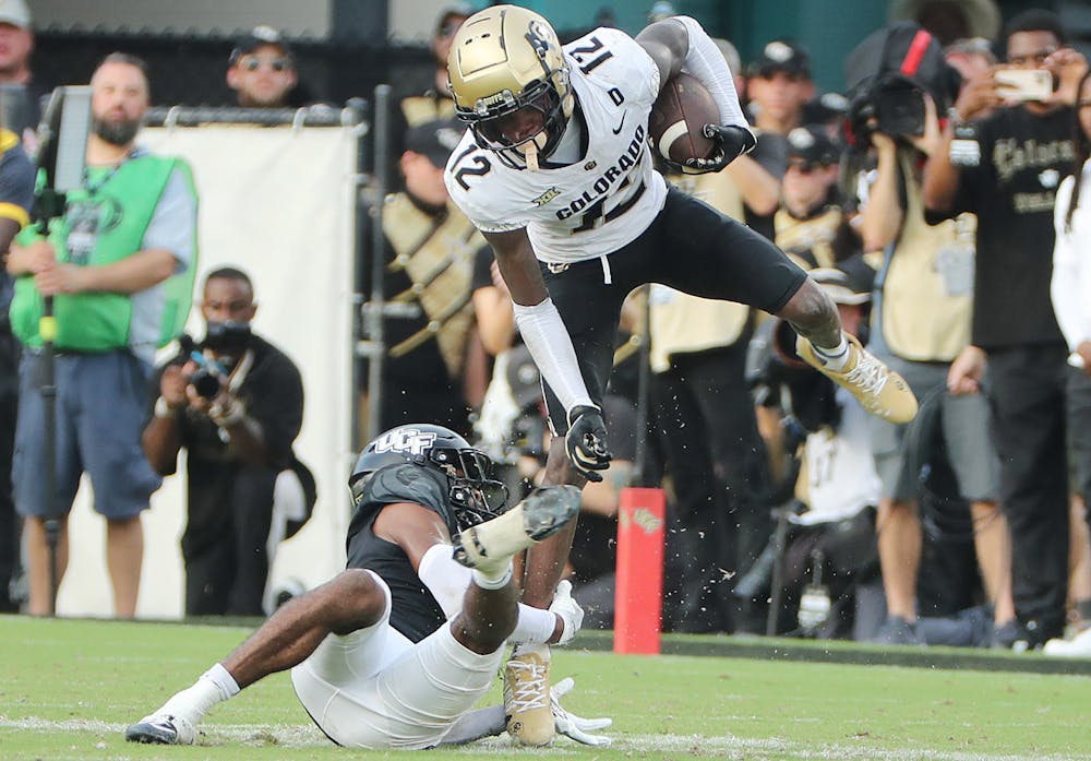 Colorado receiver Travis Hunter (12) leaps over UCF defensive back Antione Jackson (bottom) during the Colorado at UCF college football game at FBC Mortgage Stadium in Orlando on Saturday, September 28, 2024. (Stephen M. Dowell/Orlando Sentinel)