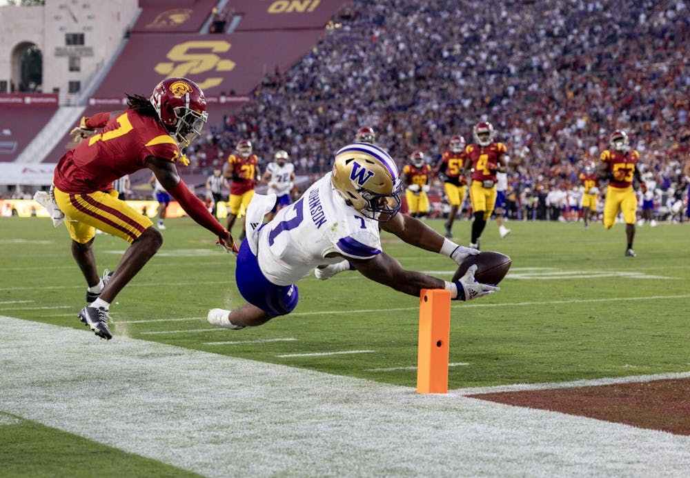 Washington Huskies running back Dillon Johnson (7) scores on a 52-yard-run against USC Trojans safety Calen Bullock (7) in the second quarter at the L.A. Memorial Coliseum Nov. 4, 2023 in Los Angeles, California.(Gina Ferazzi / Los Angeles Times)
