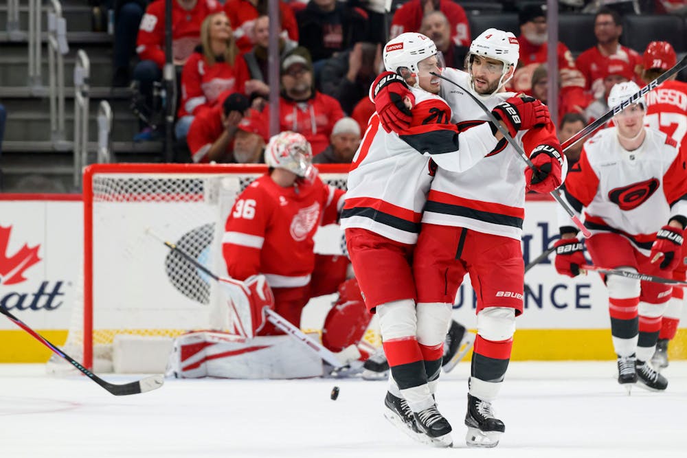 Carolina center Sebastian Aho, left, and defenseman Shayne Gostisbehere celebrate after Gostisbehere scored a goal during the third period of a game between the Detroit Red Wings and the Carolina Hurricanes at Little Caesars Arena, in Detroit, January 12, 2026. (David Guralnick, Detroit News, Tribune Content Agency)