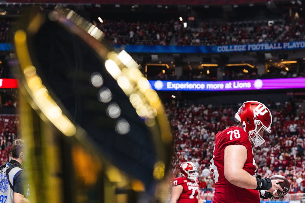 <p>With the National Championship trophy in the foreground, Indiana center Pat Coogan warms up before the College Football Playoff Semifinal at the Chick-fil-A Peach Bowl on Jan. 9 in Atlanta. (HN photo/Kallan Graybill)</p>