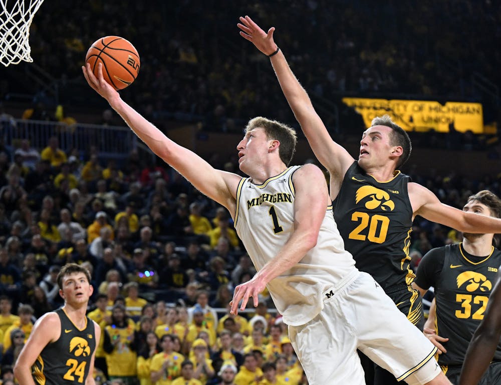 Michigan center Danny Wolf (1) drives past Iowa forward Payton Sandfort (20) in the second half. Michigan vs Iowa at Crisler Center in Ann Arbor, Mich. on December 7, 2024. Michigan wins, 85-83. (Robin Buckson, The Detroit News, Tribune Content Agency)