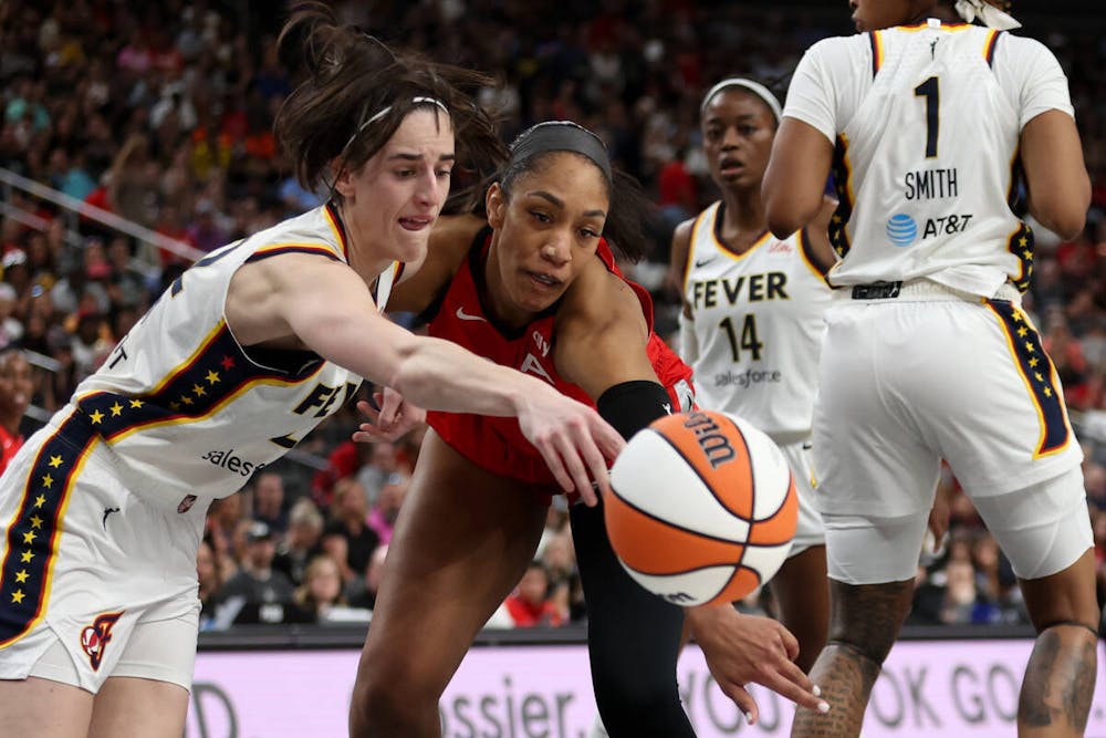 Indiana Fever guard Caitlin Clark, left, and Las Vegas Aces center A'ja Wilson, center, vie for a loose ball during the first half of a WNBA basketball game at T-Mobile Arena on Tuesday, July 2, 2024, in Las Vegas. (Ellen Schmidt/Las Vegas Review-Journal)