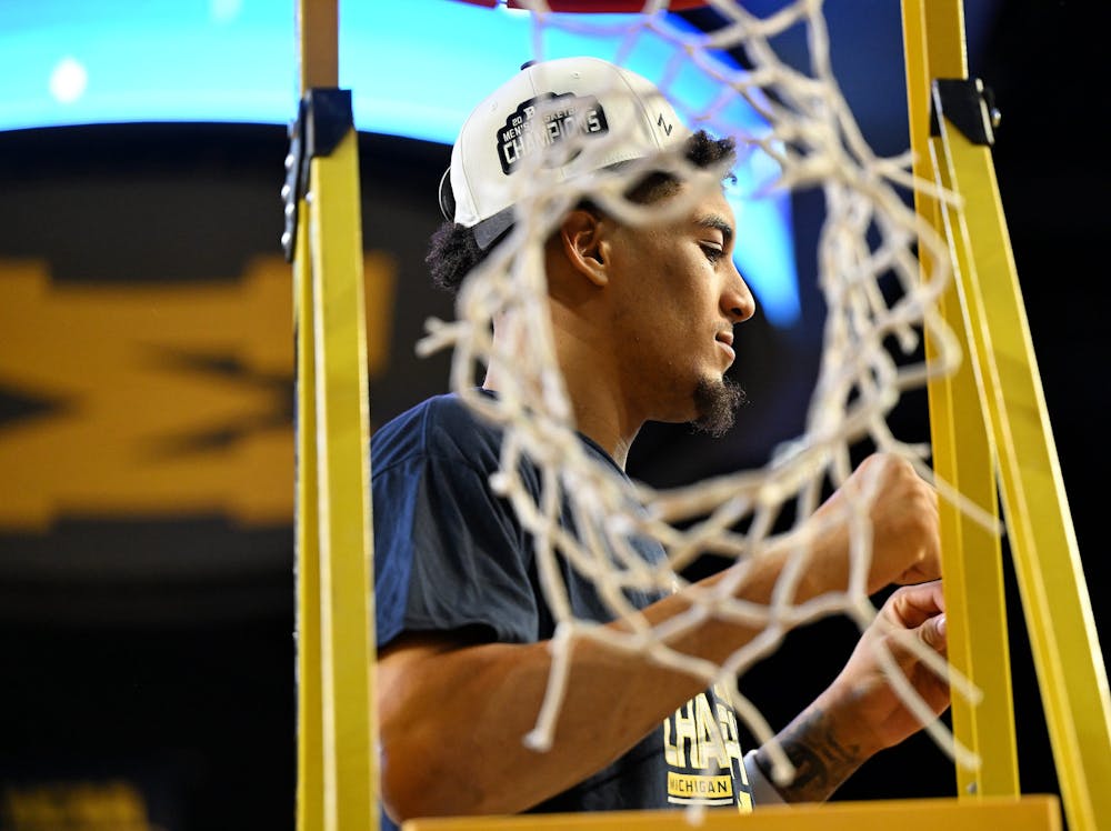 Michigan forward Yaxel Lendeborg is photographed with the cut net after a 90-80 win over Michigan State. (Robin Buckson, The Detroit News, Tribune Content Agency)