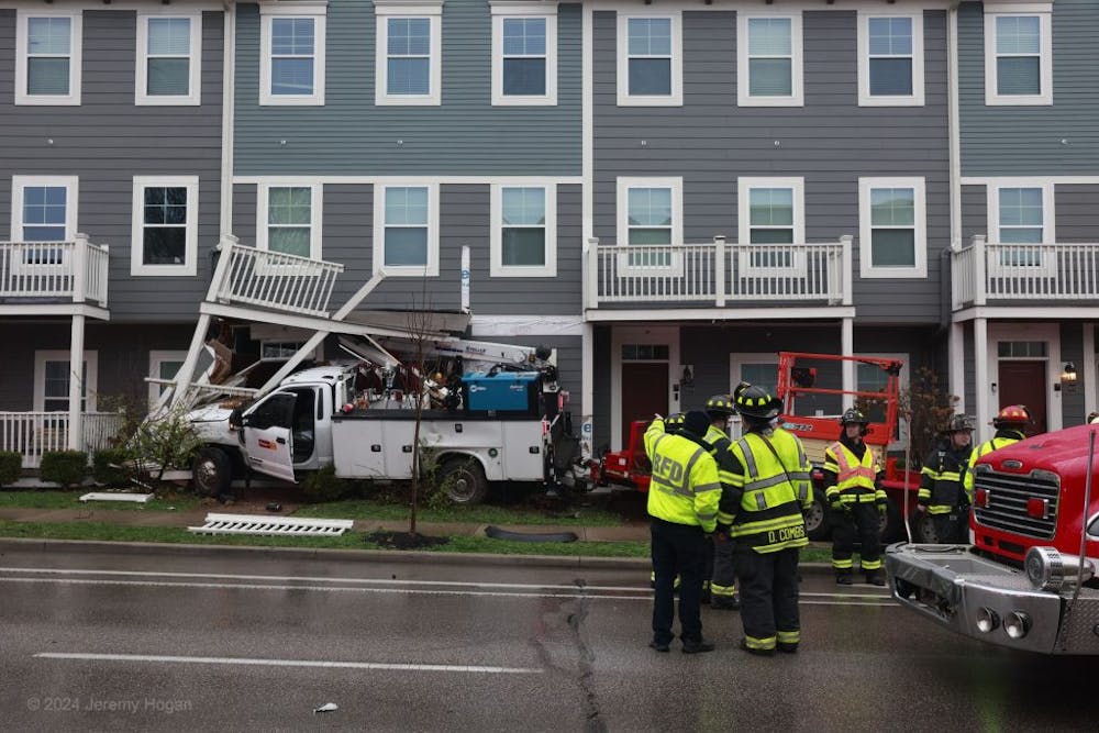 <p>Firefighters examine crash site at the Fox Row Apartments - Photo Courtesy of <em>The Bloomingtonian</em></p>