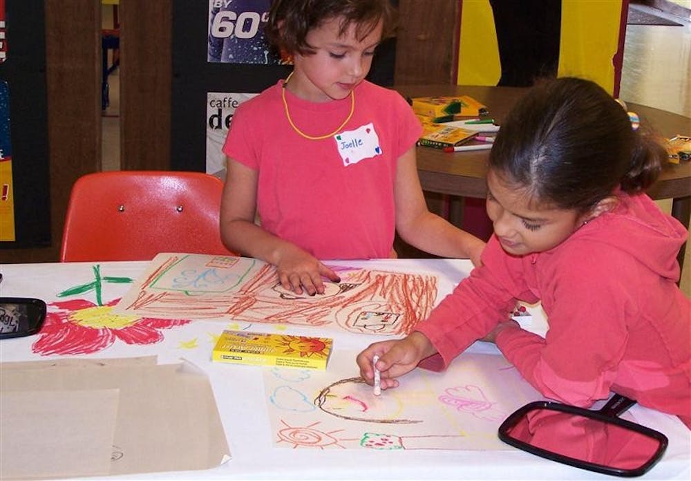 Two girls, Joelle, left, and Sofia, create a mural during a “Does the Shoe Fit?” workshop.