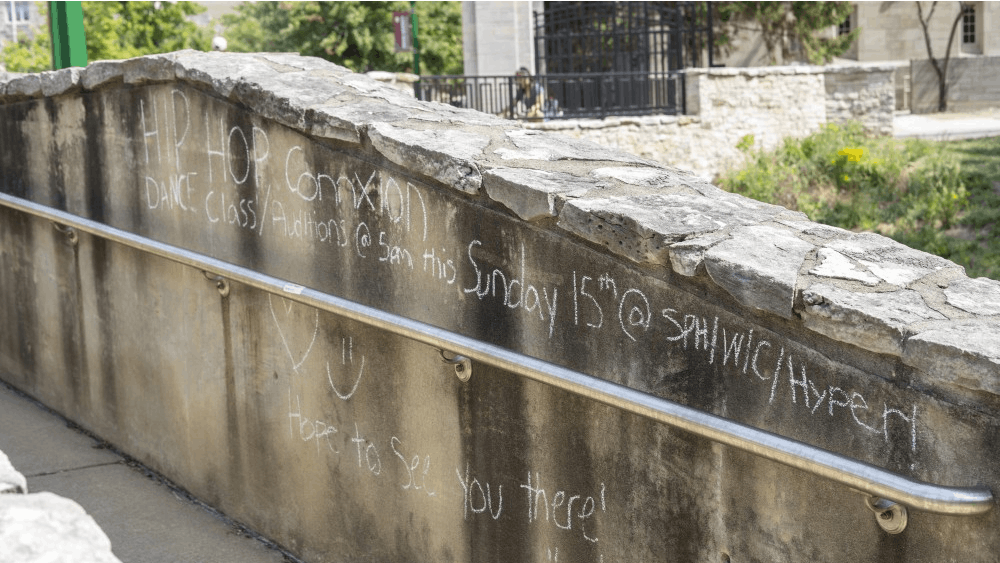 An announcement written in chalk is displayed on a wall Sept. 16 on East Seventh Street. Clubs will often write on sidewalks and walls about call-out meetings in well-trafficked areas. 